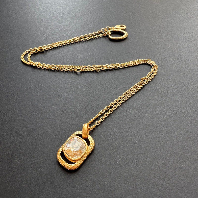 Gold-tone hammered square pendant necklace with faceted clear gemstone on chain