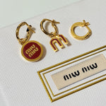Three-piece enamel hoop earrings with red round charm and gold-tone metal hoops