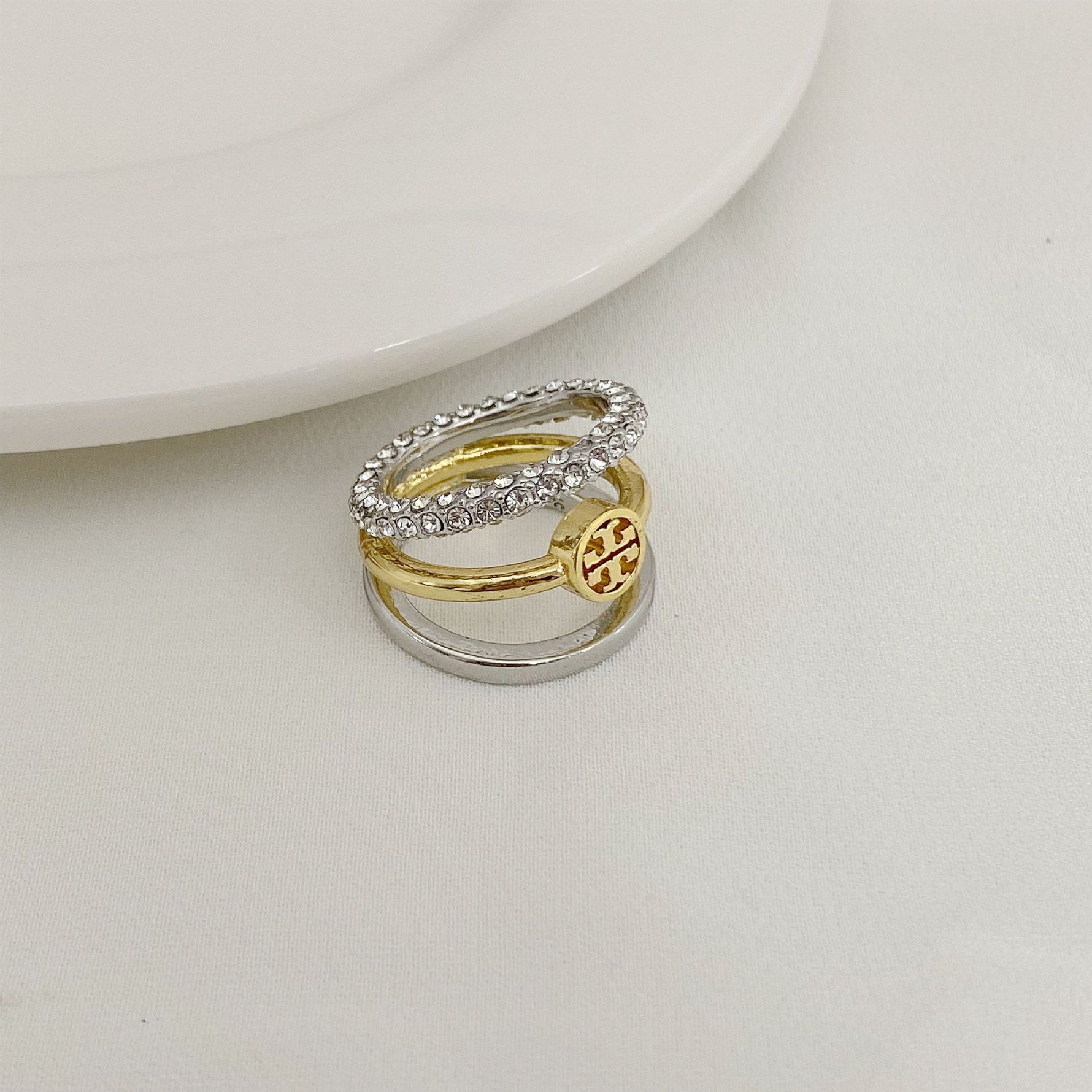 Two-tone three-band ring with silver pavé band and gold logo medallion