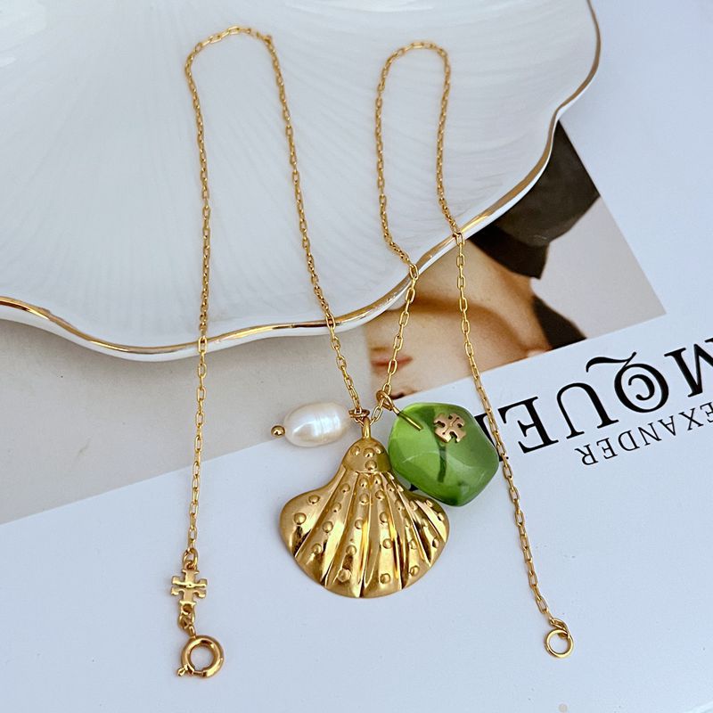 Gold-tone shell pendant necklace with green acrylic bead, white pearl, and cross charm