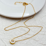 Gold necklace with round enamel pendant, white face and gold logo charm