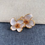 White enamel floral stud earrings with gold-tone outline and golden beaded center