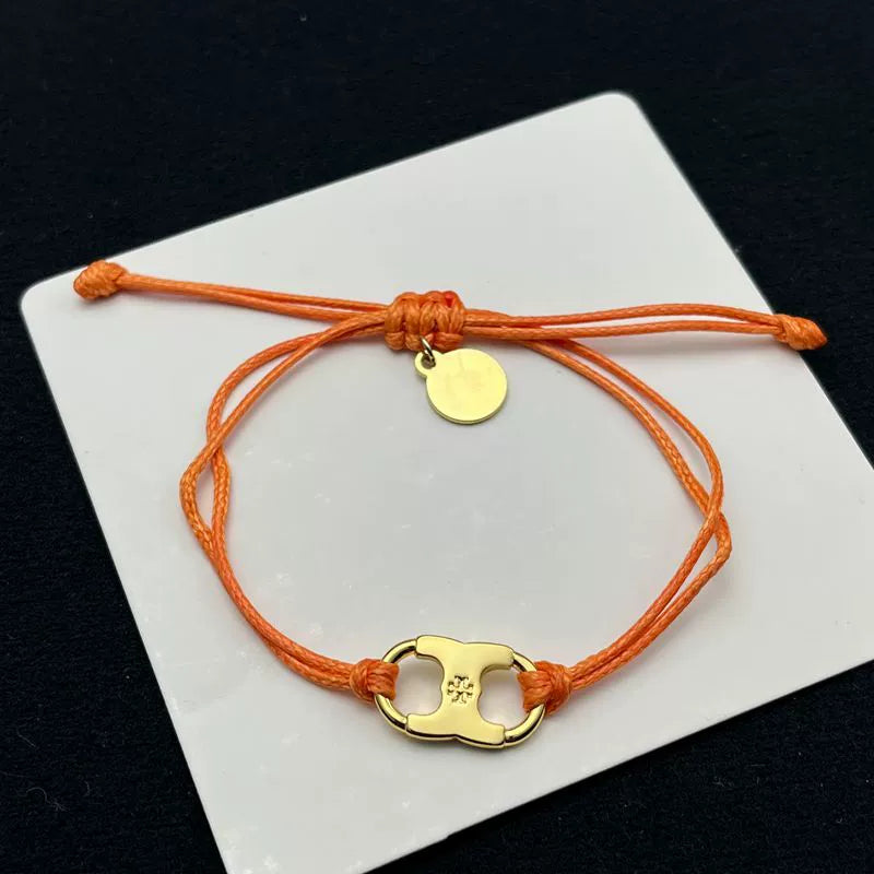 Orange woven adjustable drawstring bracelet with gold clover charm and small round tag