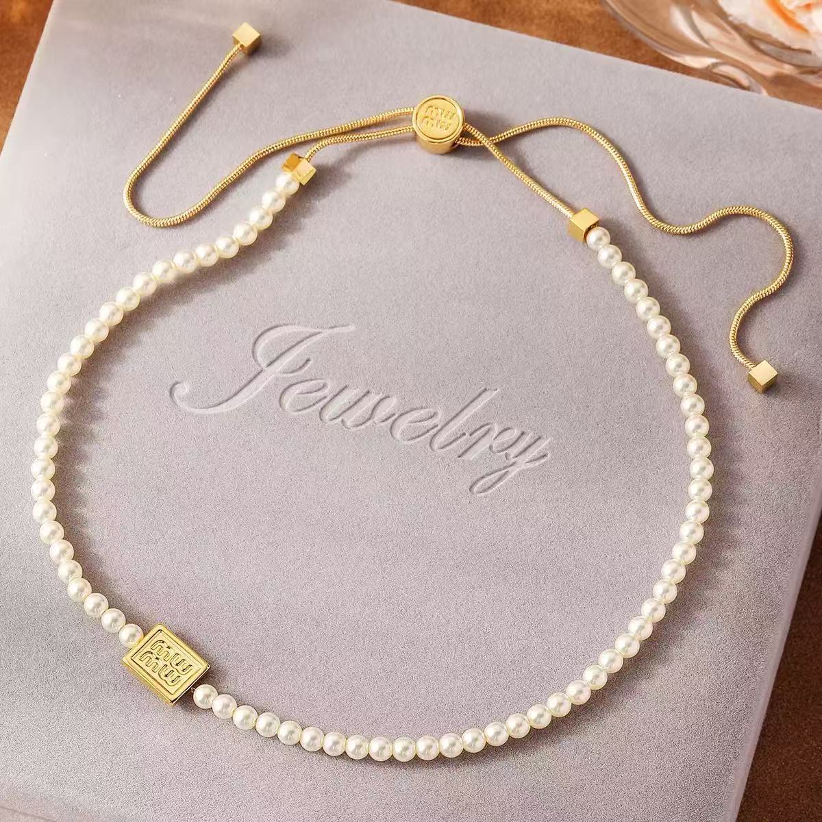 Pearl necklace strand with gold square logo tag and adjustable drawstring cord