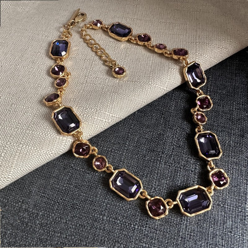 Goldfarbene Halskette mit violetten Kristallsteinen, abwechselnd eckig und rund
