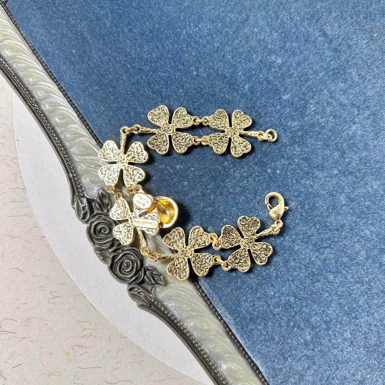 Gold-tone ladybug and clover charm bracelet with open ring end and floral links