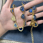 Blue heart rhinestone necklace draped on open palm, gold-tone hearts on chain