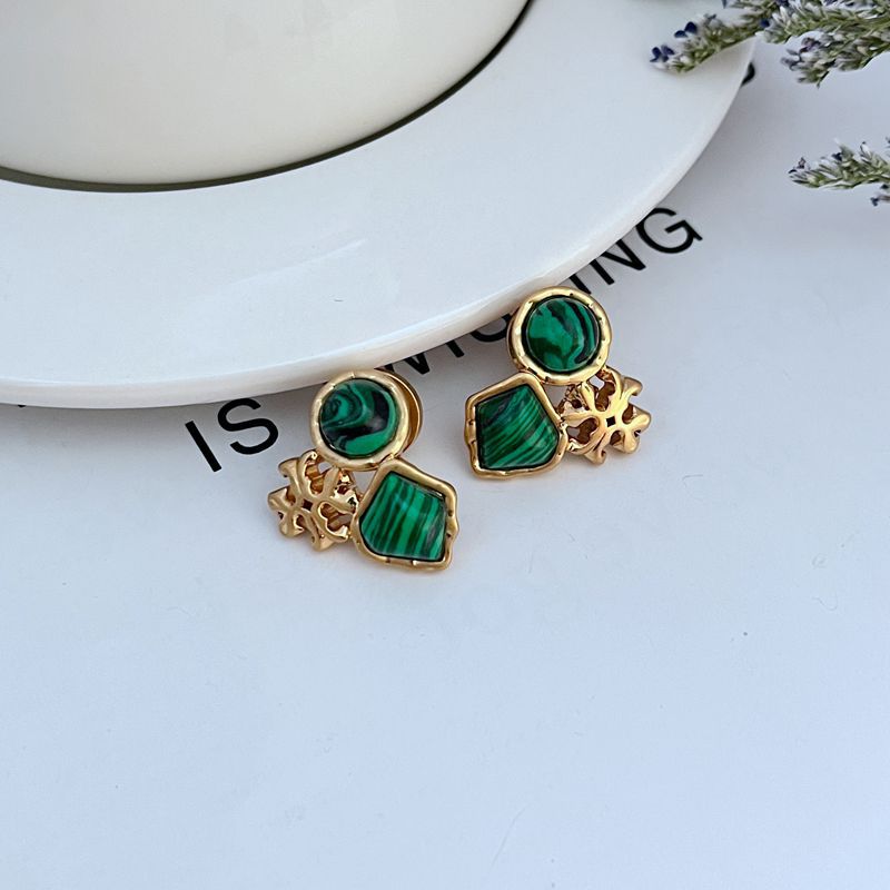 Gold-tone acrylic logo stud earrings with green stones and cutout flower studs