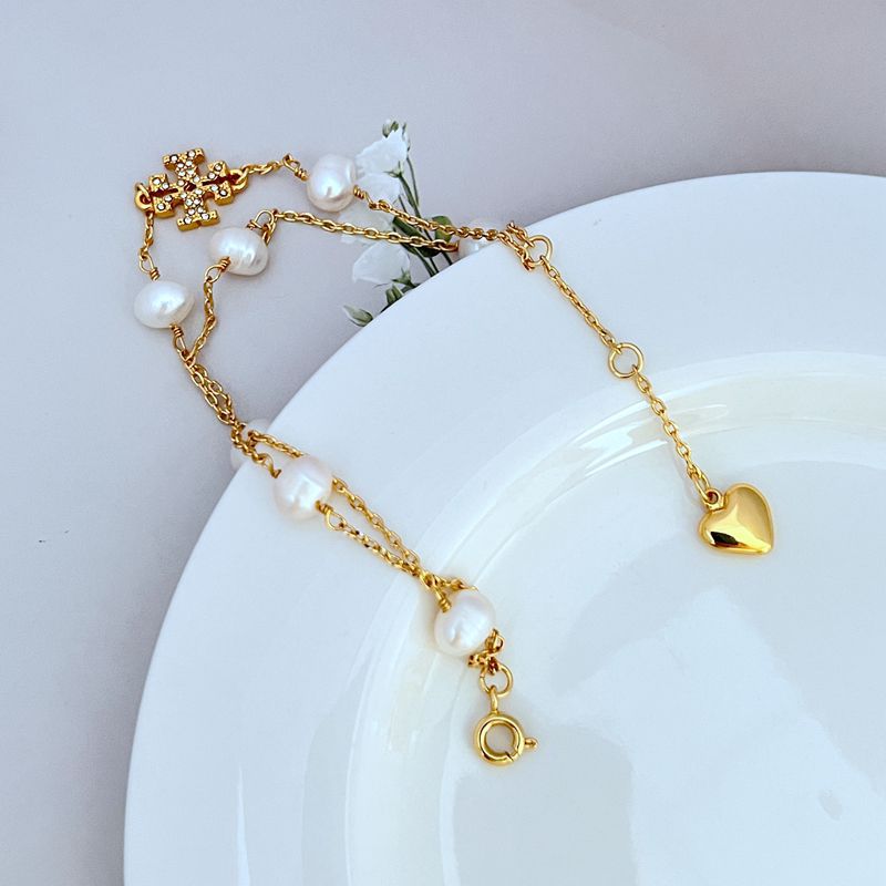 Gold bracelet with freshwater pearl drops, heart charm, and circular clasp ring