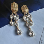 Asymmetrical crystal tassel earrings with silver-toned teardrops and gold filigree
