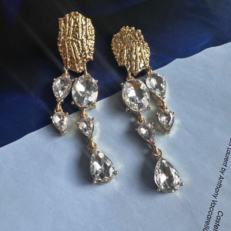 Asymmetrical crystal tassel earrings with silver-toned teardrops and gold filigree