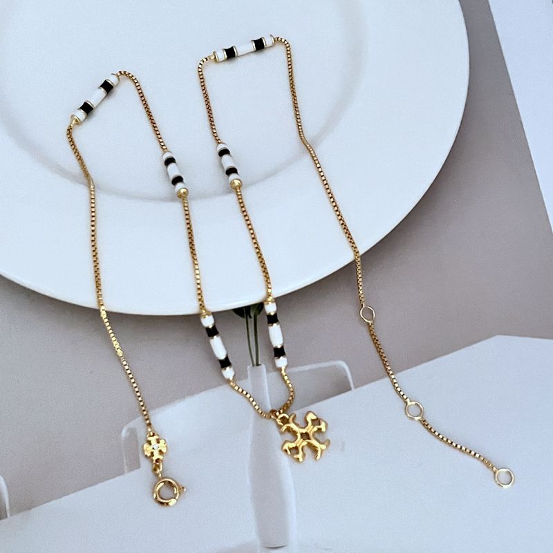 Gold-tone beaded charm necklace strand with white and black enamel stations