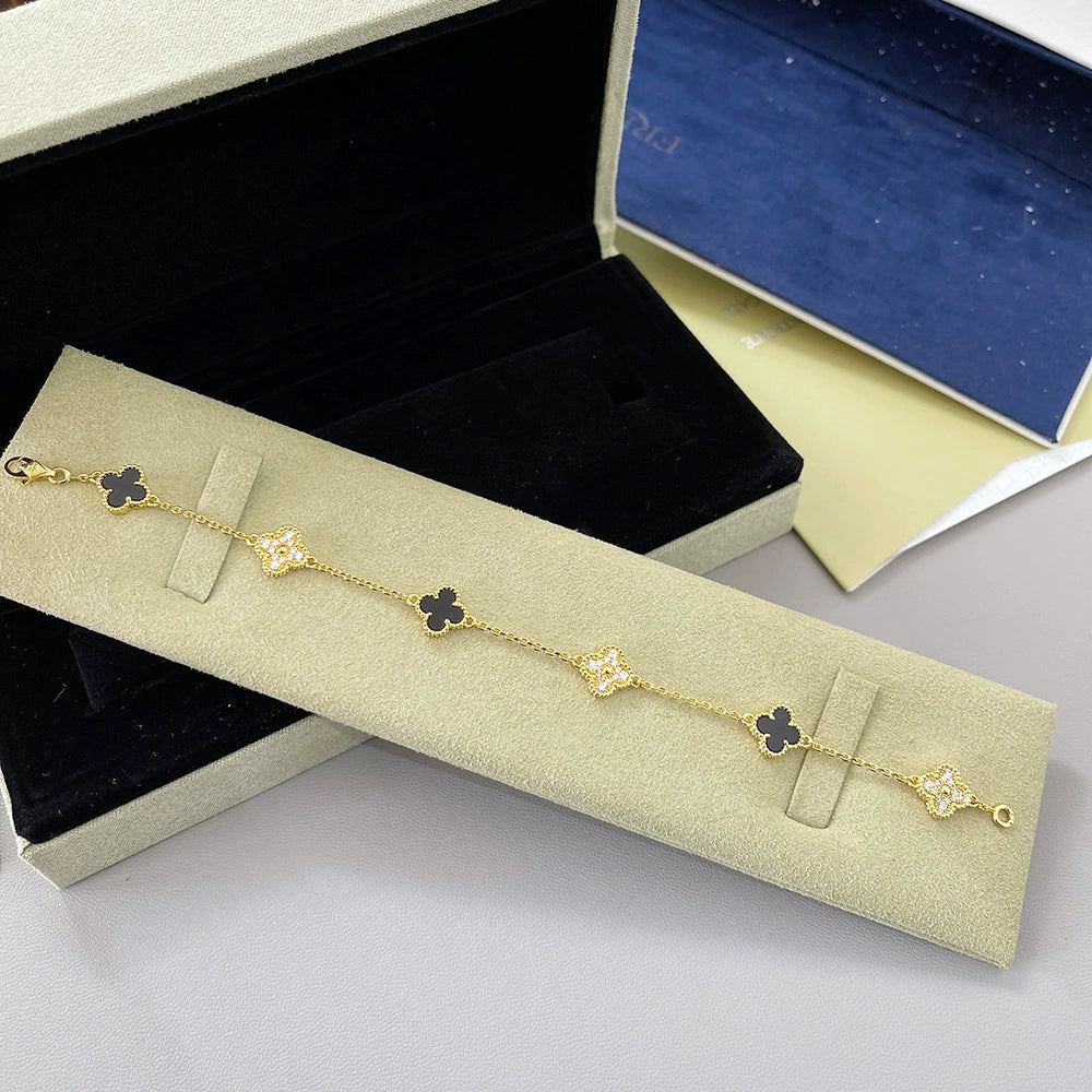 Goldfarbenes Armband mit schwarzen Vierblatt-Anhängern und glitzernden Steinelementen