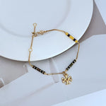 Gold-tone bracelet with yellow enamel bead stations and flower-like logo charm