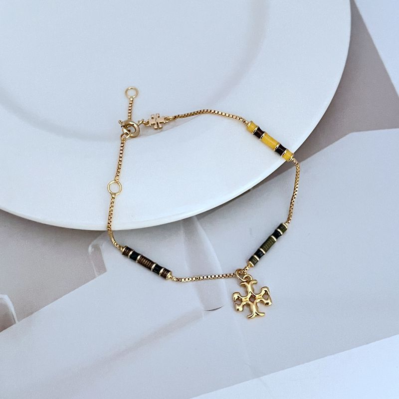 Gold-tone bracelet with yellow enamel bead stations and flower-like logo charm