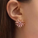 Pink enamel flower diamond earrings on gold-toned stud backs, close-up on ear