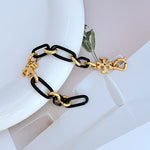Black chunky chain logo bracelet with gold-tone links and quatrefoil charms