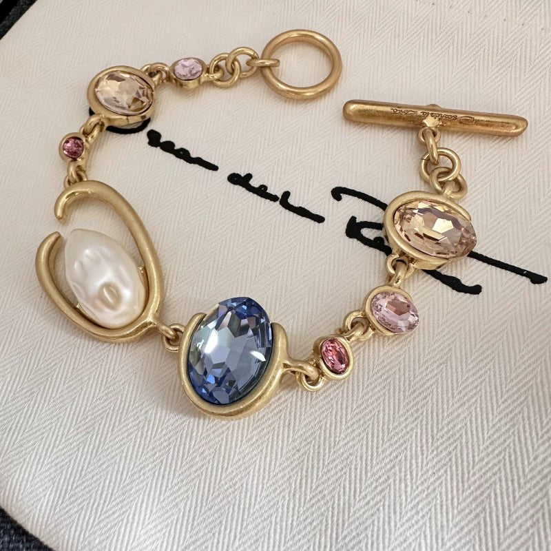 O-ring crystal pearl bracelet, gold tone with blue oval center stone, pink accents, pearl