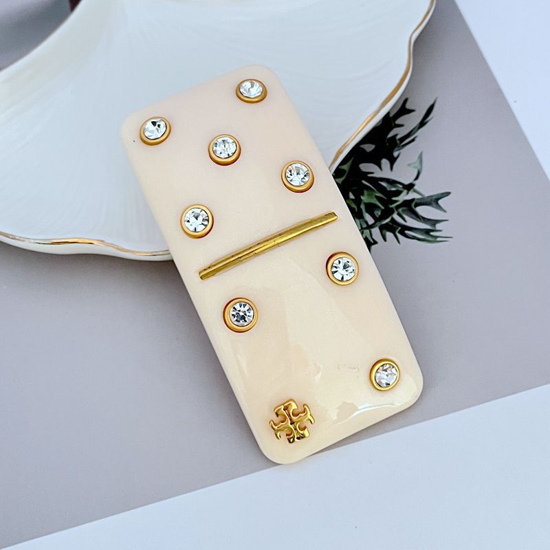 Off-white rectangular hair clip with gold bar and round crystal studs