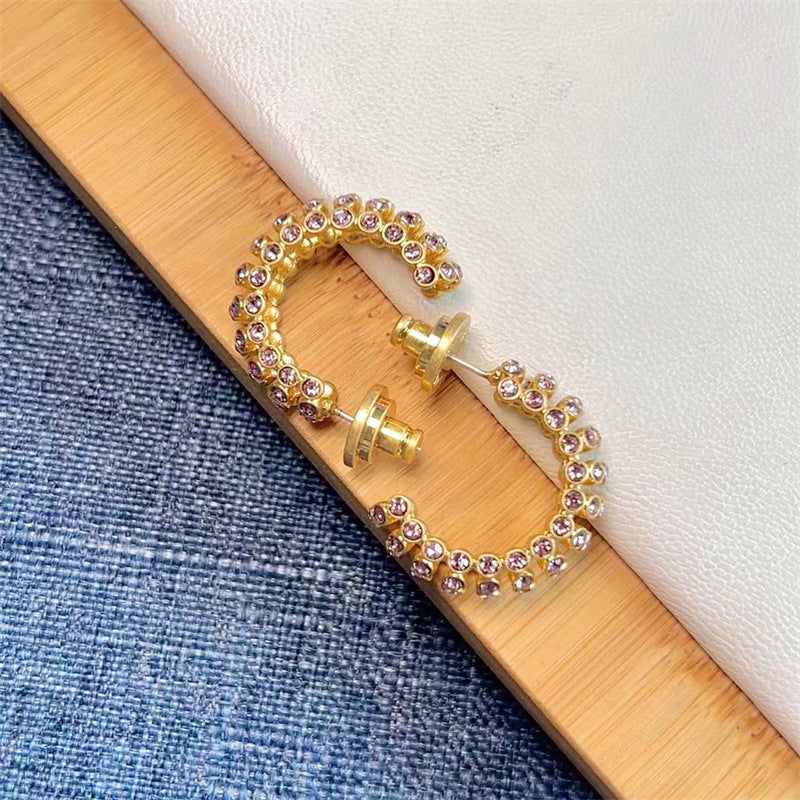 Gold-tone cubic zirconia C-hoop earrings with pink stones; curved hoop detail