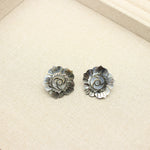 Close-up of flower-shaped mother-of-pearl stud earrings in dark-gray with circular petal pattern
