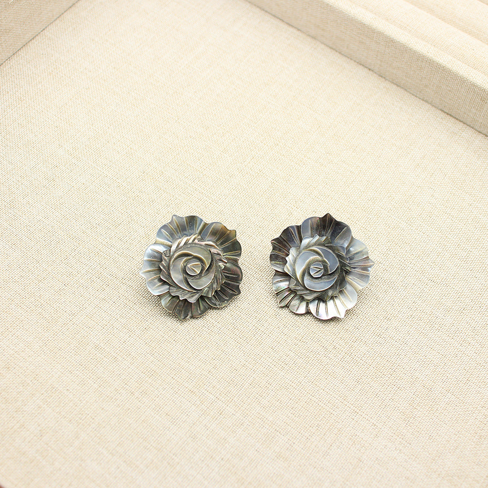 Close-up of flower-shaped mother-of-pearl stud earrings in dark-gray with circular petal pattern