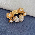Gold-tone clip-on earrings with pearl flower accents and sparkling rhinestone strawberry dangles