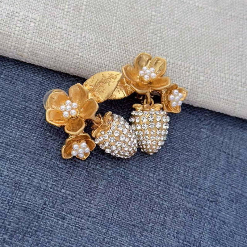 Gold-tone clip-on earrings with pearl flower accents and sparkling rhinestone strawberry dangles