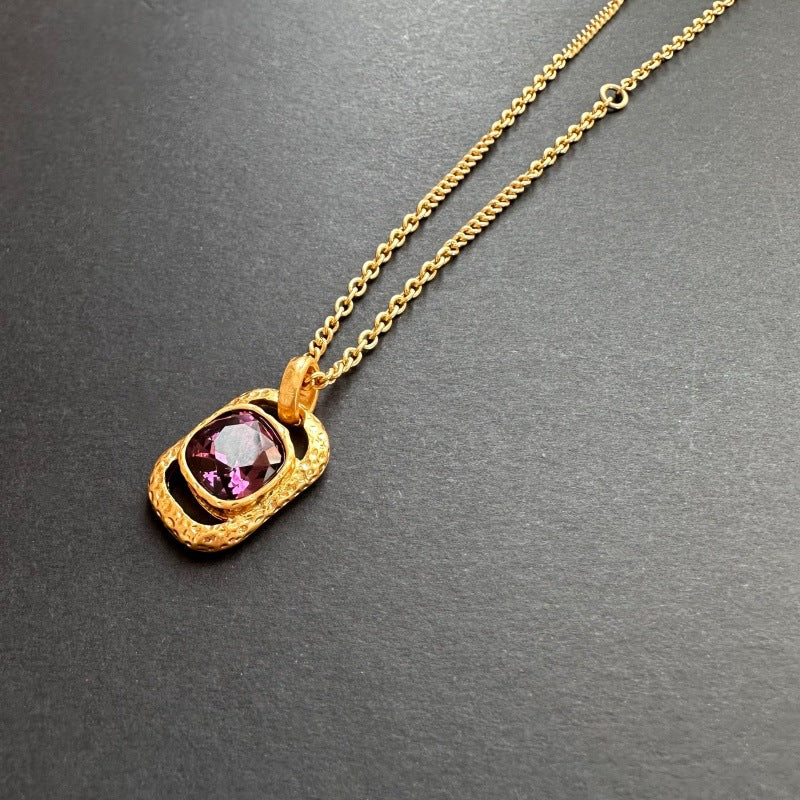 Gold-tone hammered square pendant necklace with faceted purple gemstone