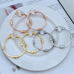 Assorted high-shine 3D logo round hoop earrings in gold, rose gold, and white gold tones