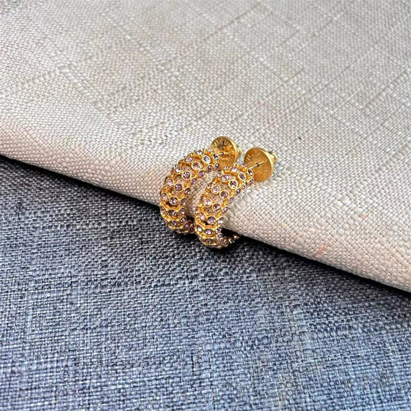 Gold-tone cubic zirconia C-hoop earrings with warm-toned stones; stud backs visible