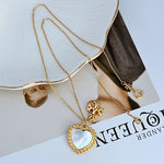 Layered gold necklace with mother-of-pearl heart pendant and small rosette charm detail