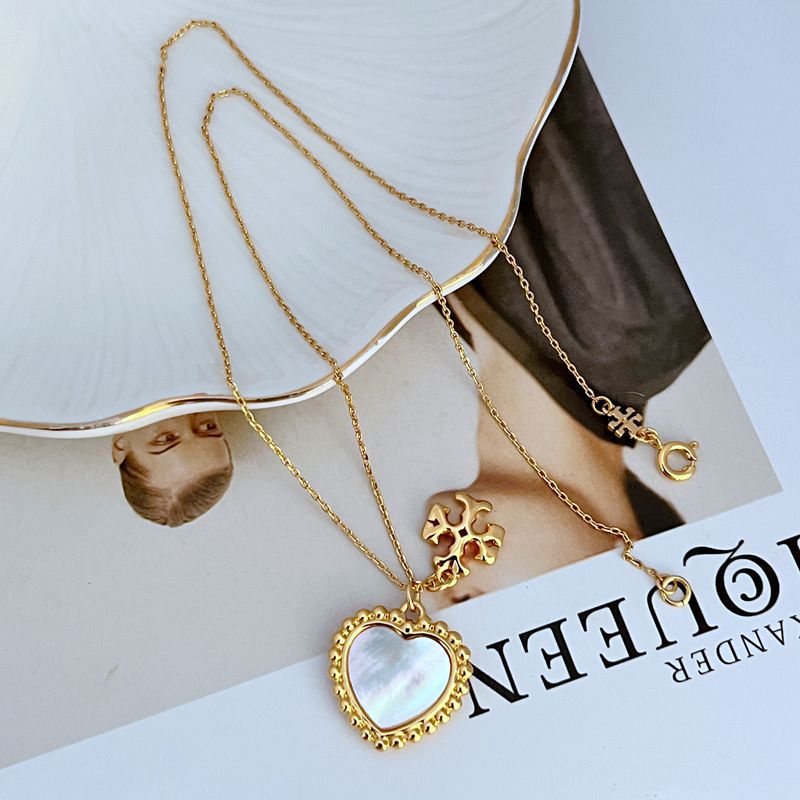 Layered gold necklace with mother-of-pearl heart pendant and small rosette charm detail