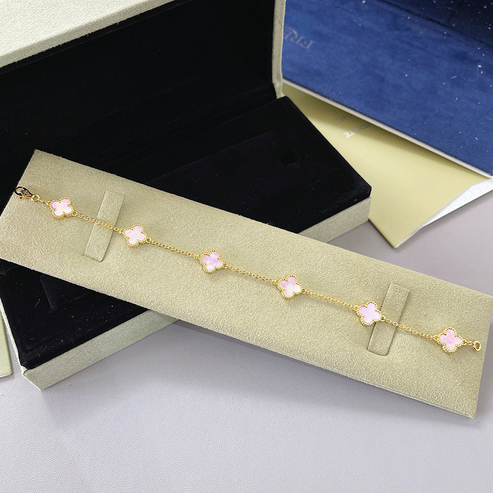Gold tone bracelet with light pink clover charms and clasp on a fine chain