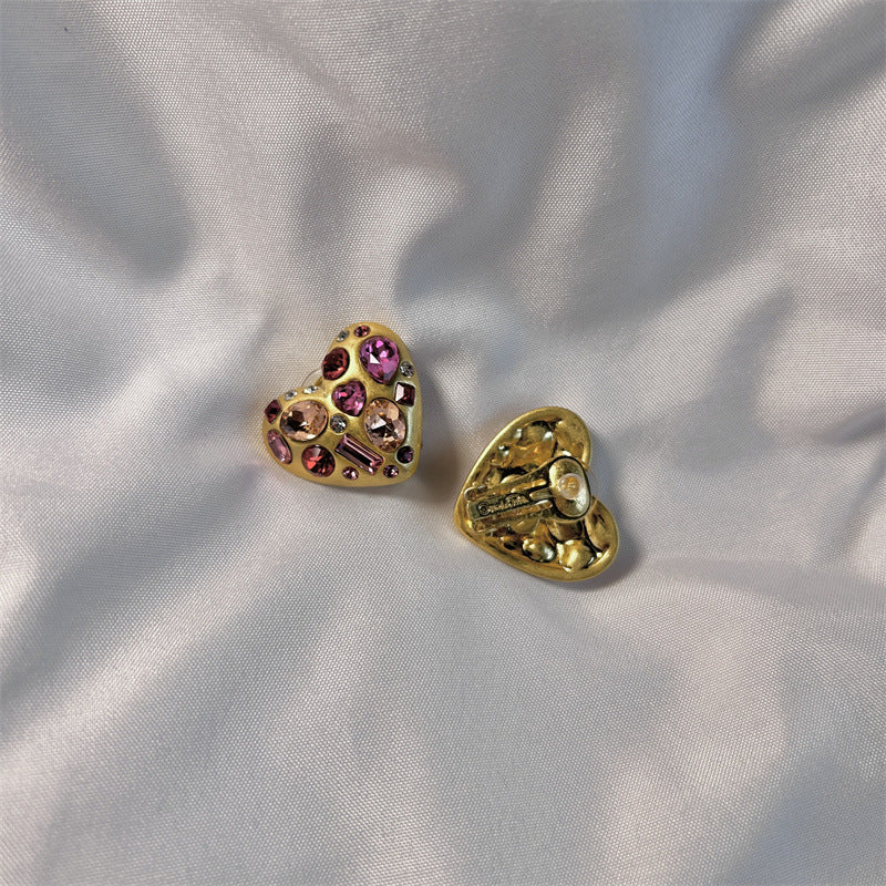 Heart-shaped crystal stud earrings in gold tone with pink-purple stones; pair shown side by side