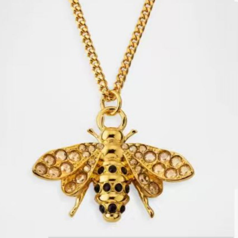 Gold bee pendant necklace featuring rhinestone-studded wings and black spot detailing