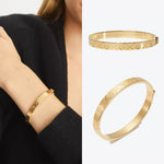 Gold Tory Burch logo-pattern bangle bracelet worn on wrist