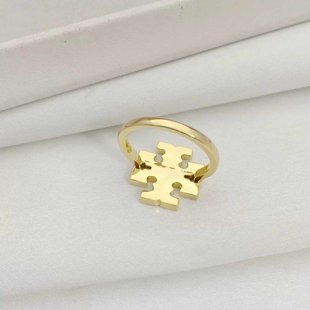 Gold logo ring with geometric cutout design on the front panel