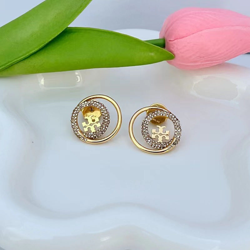 Gold rhinestone star-trail stud earrings with round logo in gold-tone setting
