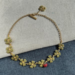 Goldtone necklace with green textured four-leaf clovers and a red ladybug charm