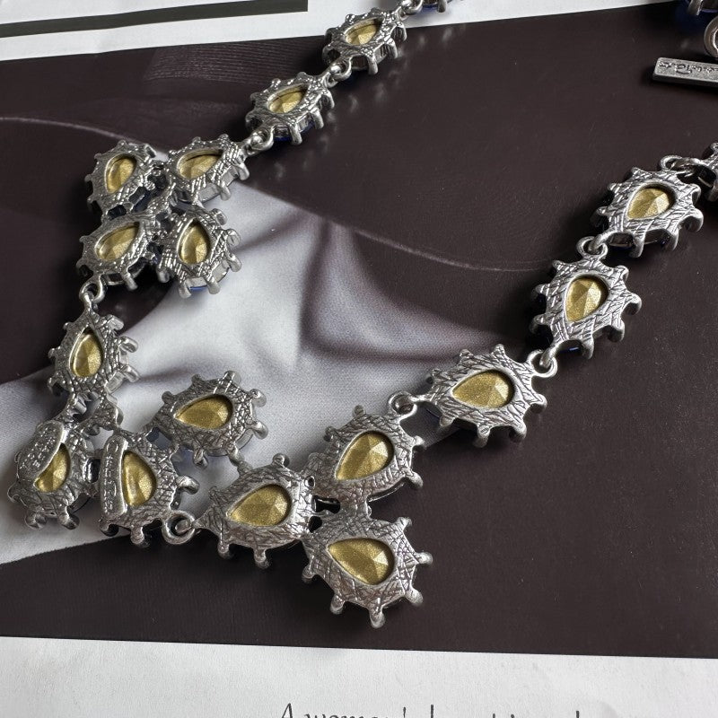 Silver-tone crystal necklace with oval cutouts and gold-toned insets on link chain