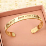 Gold openwork logo bangle with shiny curved band and cutout design details