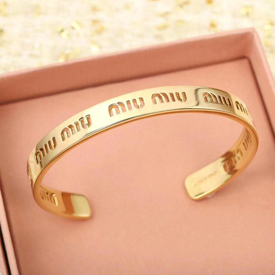 Gold openwork logo bangle with shiny curved band and cutout design details