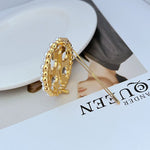 Gold hair clip with pearl bead edge and two-prong pin, circular openwork logo