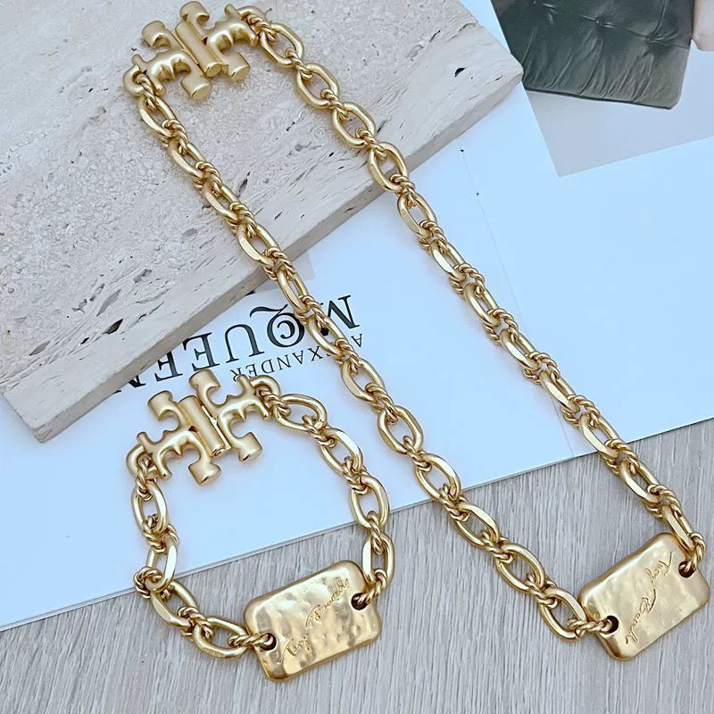 Gold chunky chain bracelet with rectangular logo tags and bold interlinked links