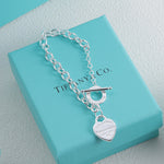 Silver bracelet with blue enamel heart charm and round charm tag