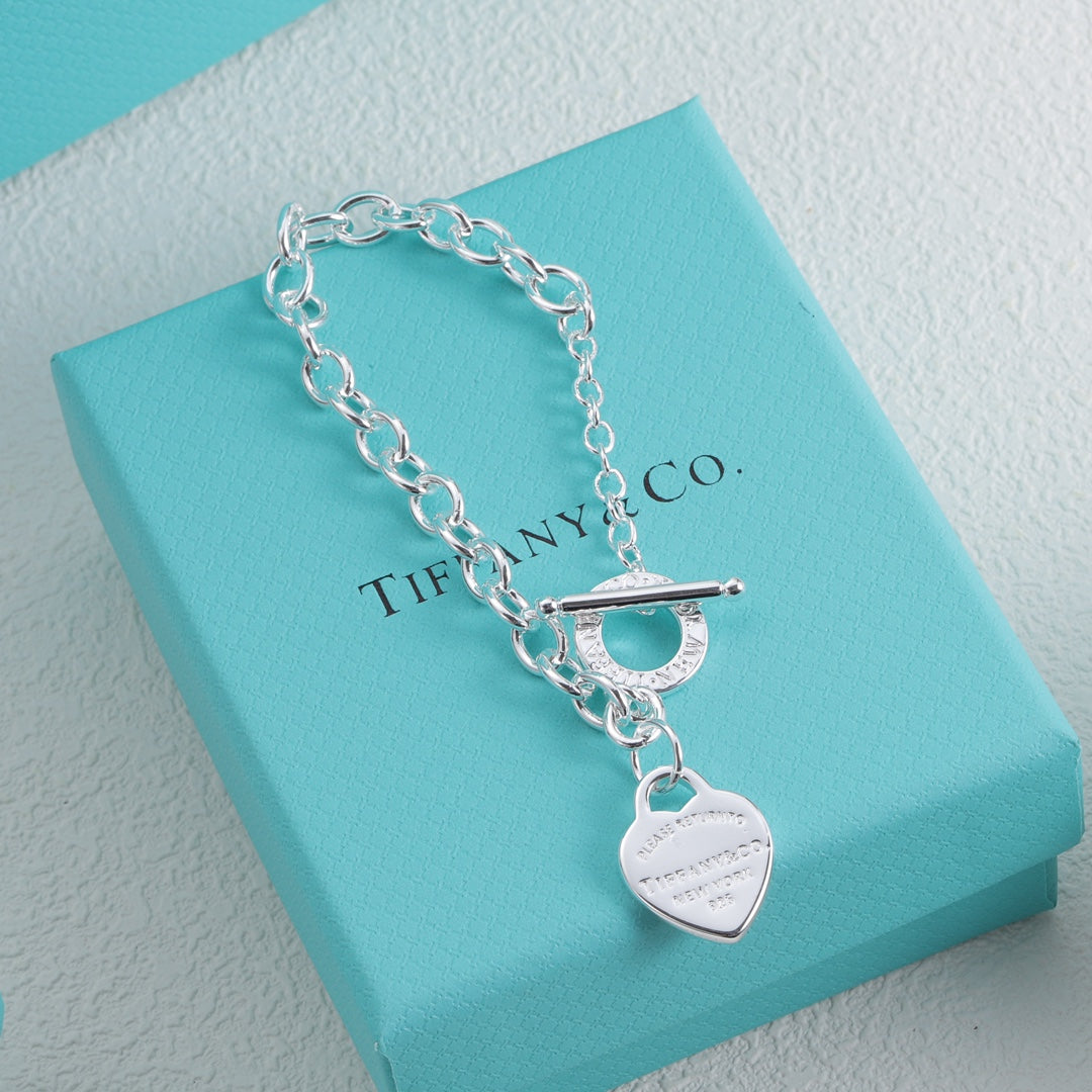 Silver bracelet with blue enamel heart charm and round charm tag