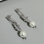 Silver-tone earrings with white pearls, rhinestone bar and bow spike tips