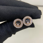 Round diamond-studded stud earrings in rose-gold tone, on dark knit fabric