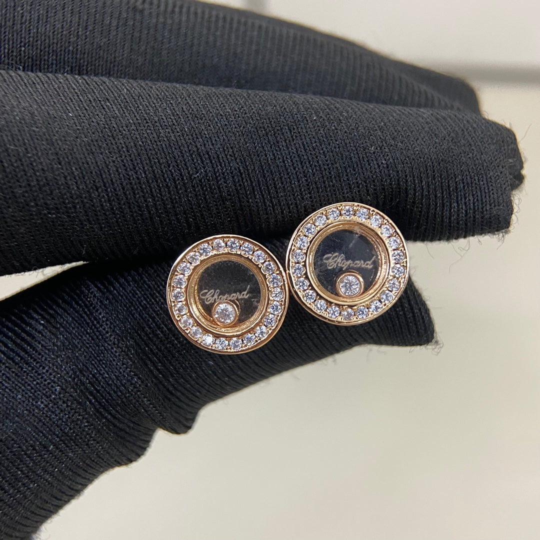 Round diamond-studded stud earrings in rose-gold tone, on dark knit fabric
